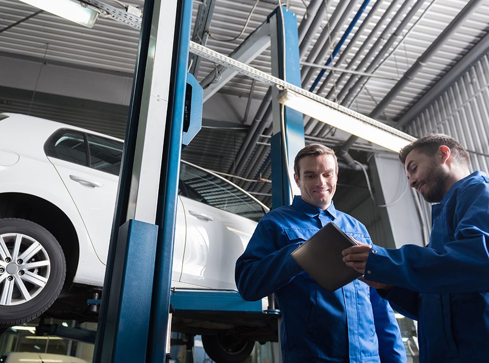 Two mechanics looking at a tablet inspecting a vehicle - Car Servicing West Norwood